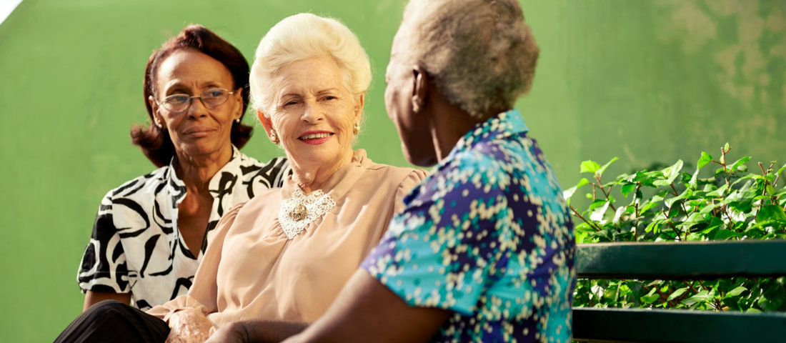 Group of elderly black and caucasian women talking in park